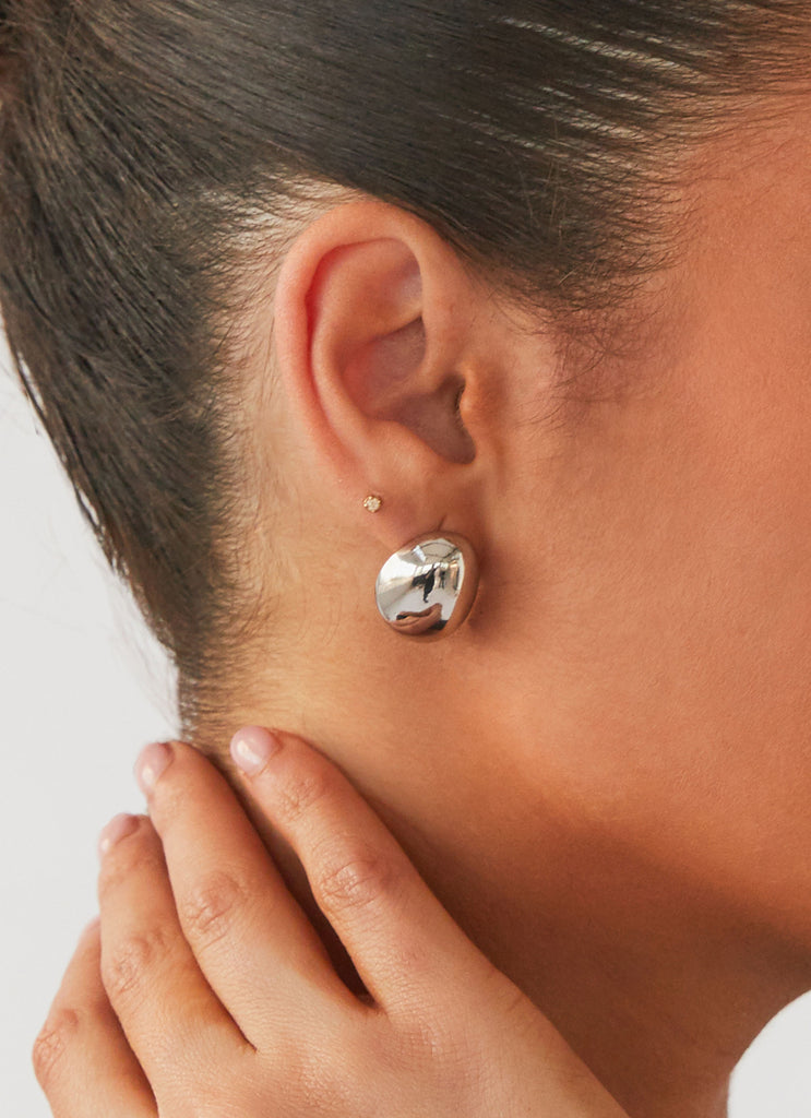 Womens Take A Bow Chunky Stud Earrings in the colour Silver in front of a light grey background