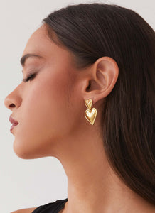 Womens Diah Heart Earrings in the colour Gold in front of a light grey background