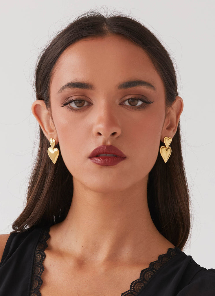 Womens Diah Heart Earrings in the colour Gold in front of a light grey background