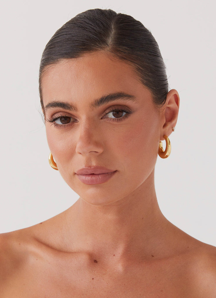 Womens Calisse Hoop Earrings in the colour Gold in front of a light grey background