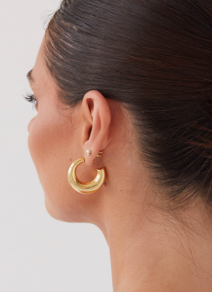 Womens Calisse Hoop Earrings in the colour Gold in front of a light grey background