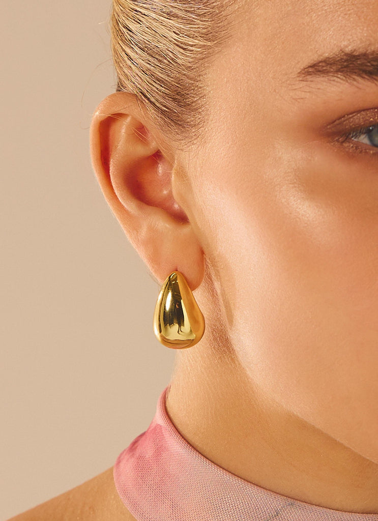 Womens Big Energy Earrings in the colour Gold in front of a light grey background